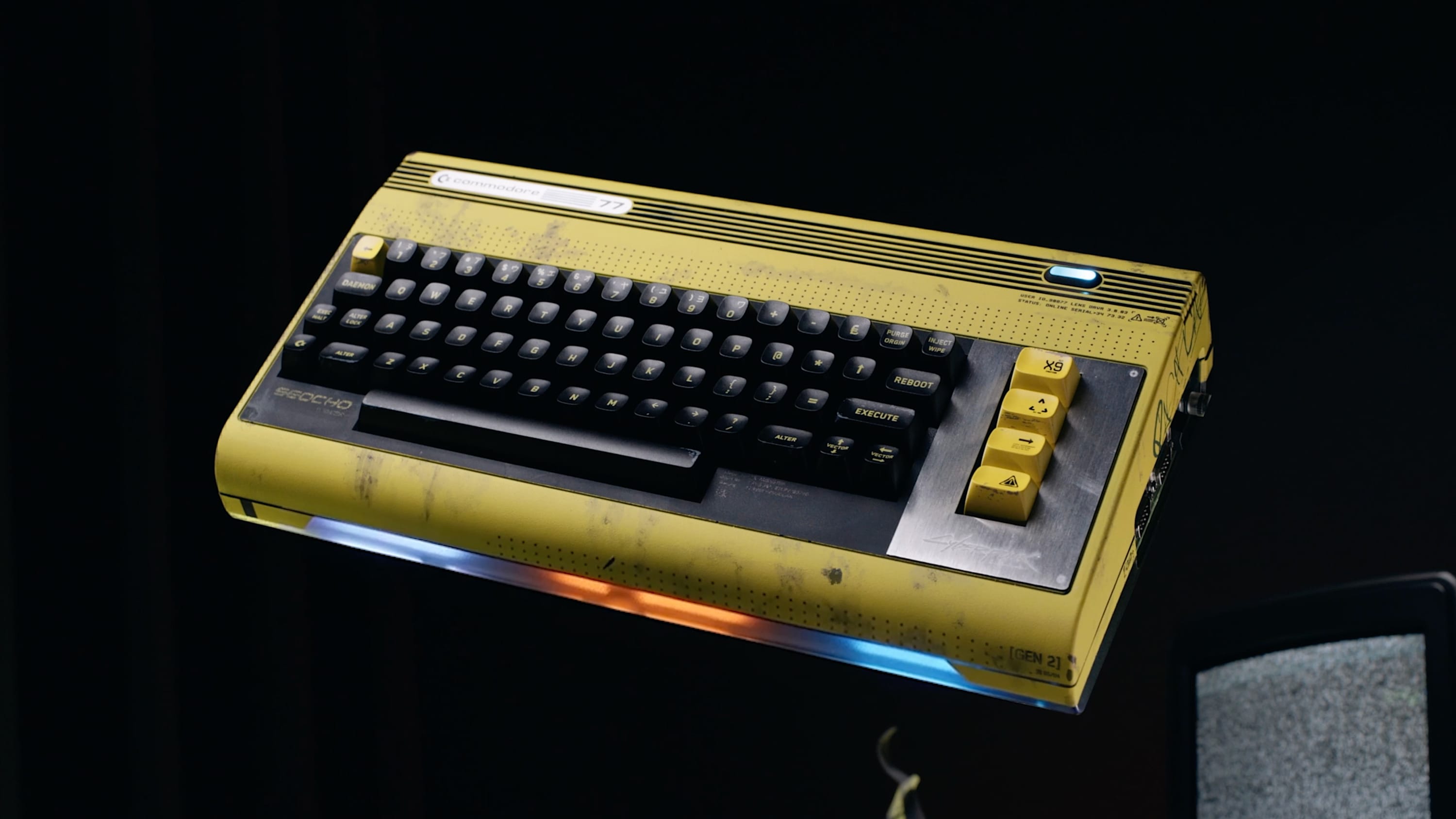 Offizielles Produktbild des Commodore 77 aus schräger Draufsicht mit angepassten Tastenbeschriftungen und gebürsteter Metallfläche